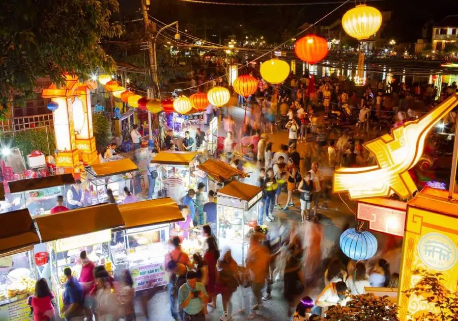 A bustling scene of the Hoi An night market with colorful stalls.