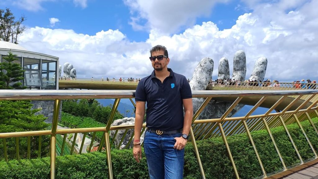 Golden Bridge at Ba Na Hills with giant hands and green mountains in the background