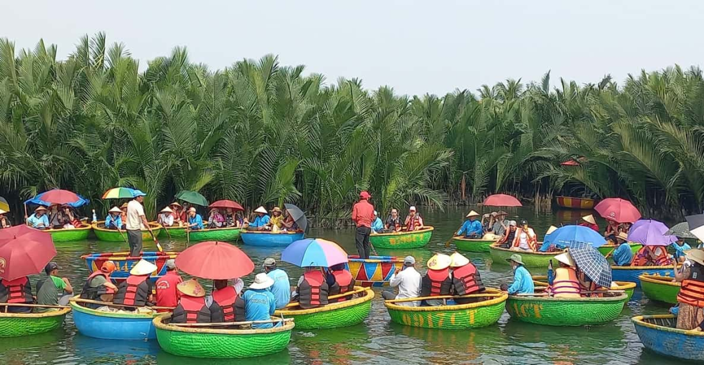 Group of tourists in bamboo basket boats gliding through canals on the best coconut boat tour in Cam Thanh Village, Hội An, surrounded by lush coconut palms.